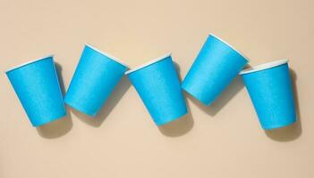 Blue disposable cups for coffee and tea on a beige background, top view photo