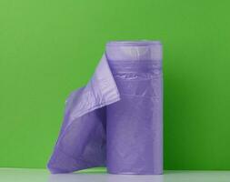 Purple plastic trash bags with strings on white background, close up photo