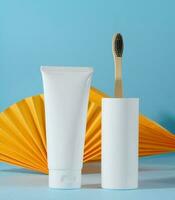 White plastic toothpaste tube and toothbrush on a blue background photo