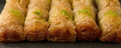 piezas de horneado baklava en miel y rociado con pistachos en un negro tablero foto