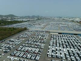 Aerial view of new cars stock at factory parking lot. Above view cars parked in a row. Automotive industry. Logistics business. Import or export new cars at warehouse. Big parking lot at port terminal photo