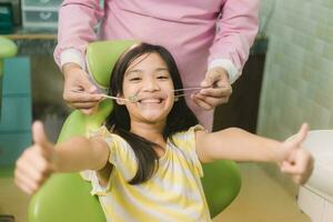 Portrait of happy asian girl shows thumb up gesture at dental clinic photo