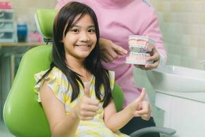 Portrait of happy girl shows thumb up gesture at dental clinic photo