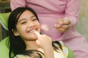 linda asain niña durante dental tratamiento a moderno clínica foto