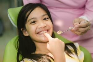 linda asain niña durante dental tratamiento a moderno clínica foto