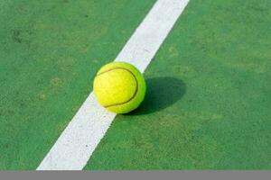 amarillo tenis pelota en verde Corte y blanco líneas. parte superior ángulo ver de tenis pelota en corte. foto