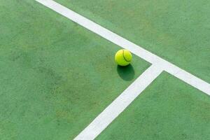 amarillo tenis pelota en verde Corte y blanco líneas. parte superior ángulo ver de tenis pelota en corte. foto