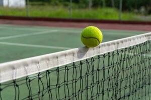 cerca arriba de tenis pelota clips el parte superior de el neto. tenis pelota golpear el red y va a el otro lado. foto