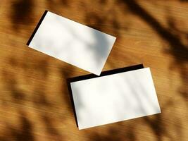 Clean minimal business card mockup with the leaves shadow on wood table background photo