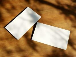 Clean minimal business card mockup with the leaves shadow on wood table background photo