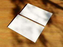 Clean minimal business card mockup with the leaves shadow on wood table background photo