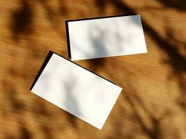 Clean minimal business card mockup with the leaves shadow on wood table background photo