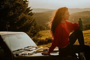 Young woman relaxing on a terrain vehicle hood at countryside photo