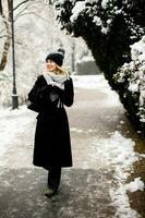 Young woman in warm clothes enjoying in snow with takeaway coffee cup photo