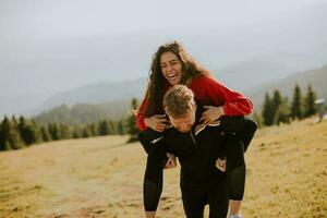 joven mujer montando a cuestas en un novio a verde colinas foto