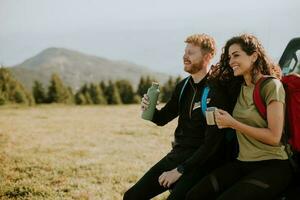 Smiling couple preparing hiking adventure with backpacks by terrain vehicle photo