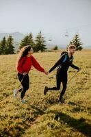 Young couple walking with backpack over green hills photo