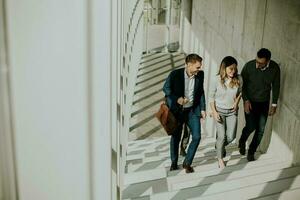 Group of corporate business professionals climbing at stairs in office corridor photo