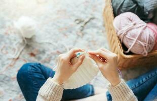 Young woman knitting warm scarf indoors photo