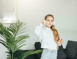 linda pequeño niña escuchando a música en auriculares foto