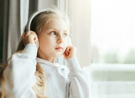 Little girl with headphones indoors at home photo