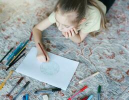 Child girl drawing with colorful pencils photo