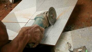 Asian hand cutting floor tiles using hand grinder video