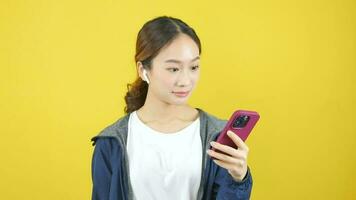 asiatico donna indossare cuffie giocando con smartphone e mostrando eccezionale cartello video