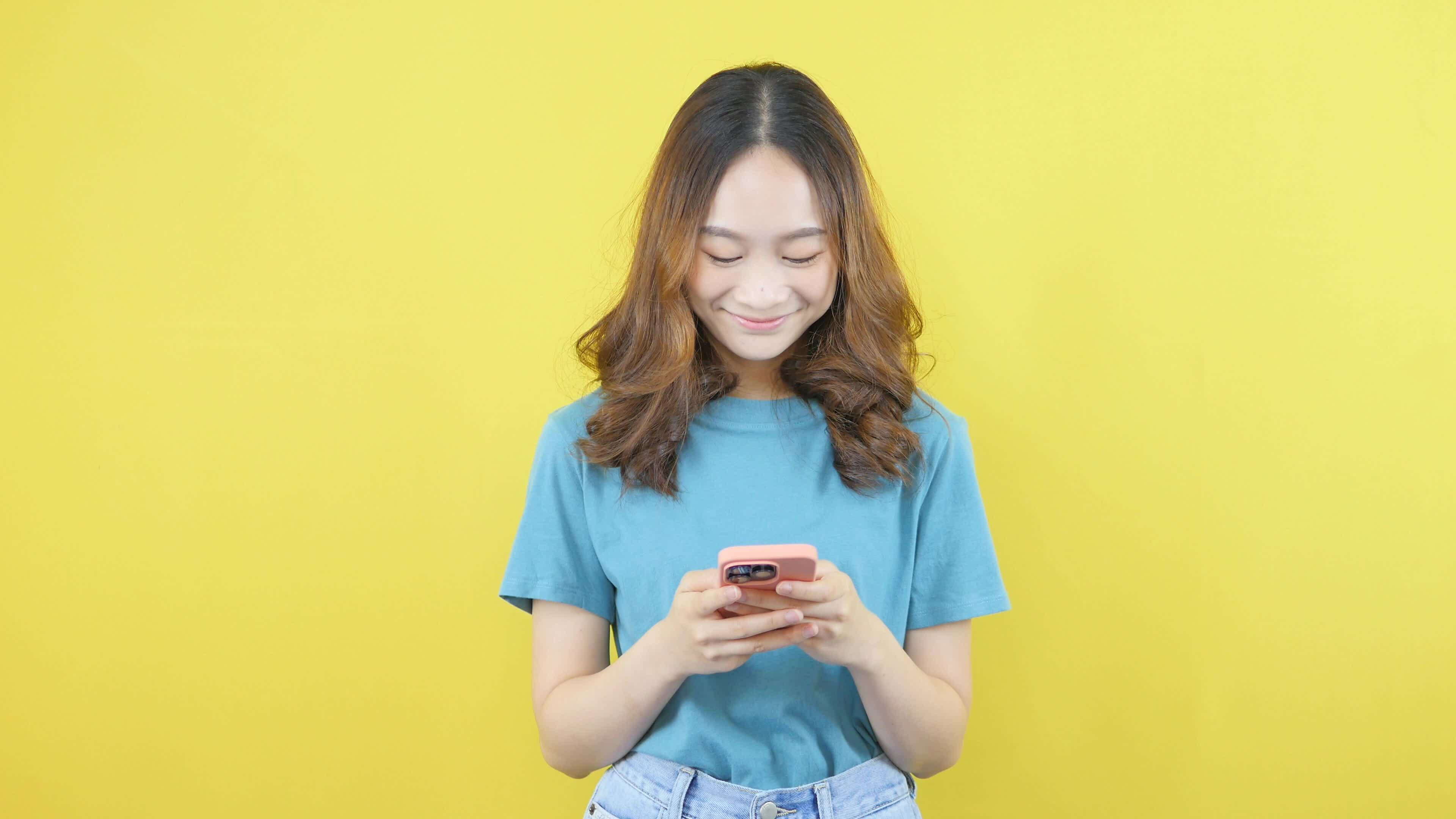 Asian woman bending down to use mobile phone to surf the world on
