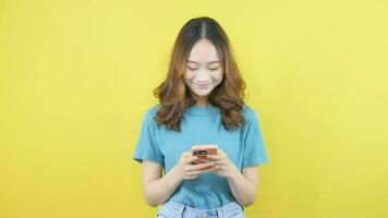 asiatisk kvinna böjning ner till använda sig av mobil telefon till surfa de värld på social media video