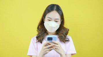 Nahansicht Video von asiatisch Frau tragen Gesicht Maske während spielen mit Smartphone.