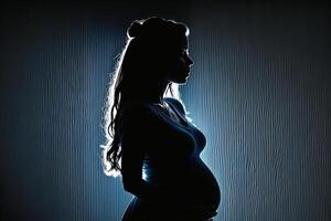 Silhouette of a pregnant woman on a dark background. photo