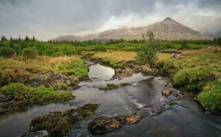 hermosa paisaje paisaje con río corriente y montañas debajo dramático nublado cielo a Connemara nacional parque en condado galway, Irlanda foto