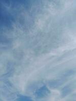 White clouds in the blue sky. Beautiful bright blue background. Light cloudy, good weather. Curly clouds on a sunny day. photo