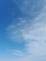 White clouds in the blue sky. Beautiful bright blue background. Light cloudy, good weather. Curly clouds on a sunny day. photo