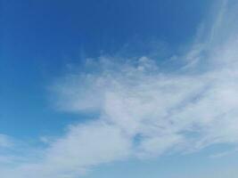 White clouds in the blue sky. Beautiful bright blue background. Light cloudy, good weather. Curly clouds on a sunny day. photo