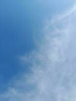 White clouds in the blue sky. Beautiful bright blue background. Light cloudy, good weather. Curly clouds on a sunny day. photo