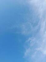 White clouds in the blue sky. Beautiful bright blue background. Light cloudy, good weather. Curly clouds on a sunny day. photo