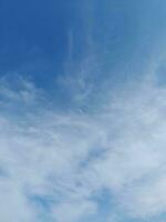 White clouds in the blue sky. Beautiful bright blue background. Light cloudy, good weather. Curly clouds on a sunny day. photo