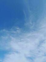 White clouds in the blue sky. Beautiful bright blue background. Light cloudy, good weather. Curly clouds on a sunny day. photo