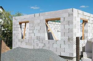 Construction of a house from gas silicate white blocks. A mountain of gravel near an unworthy house photo