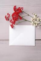 Top View of White Greeting Card, Envelope Mockup, Red Berries and Tiny Floral Branches on Wooden Table, . photo