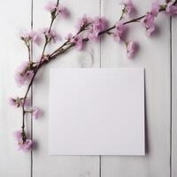 Blank White Paper Card Mockup and Cherry Blossom Branch Flat Lay on Wooden Table Top. . photo