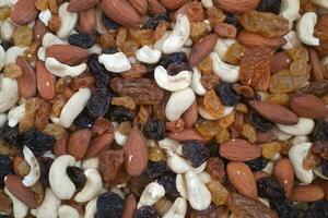 Stack of mixed nuts and dried raisins on a market stall photo