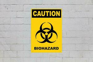 Caution, Biohazard sign on a cinder block wall photo