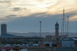 Puerto vell y el barceloneta reloj torre a puesta de sol foto