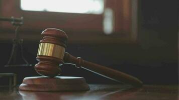 concetto di giustizia e diritto. giudice maschio in un'aula di tribunale con il martelletto, lavorando con computer e tastiera docking, occhiali, sul tavolo alla luce del mattino video