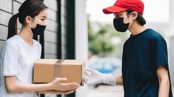 Side View Portrait of Delivery Boy Giving Cardboard Box to Female Customer in Protective Mask at Doorstep. . photo