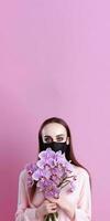 retrato de medio Envejecido mujer vistiendo máscara y participación hermosa orquídea ramo, generativo ai. foto