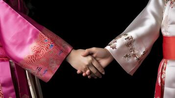 Friendly or casual handshake between Asian Cultural Women in their traditional attires. . photo